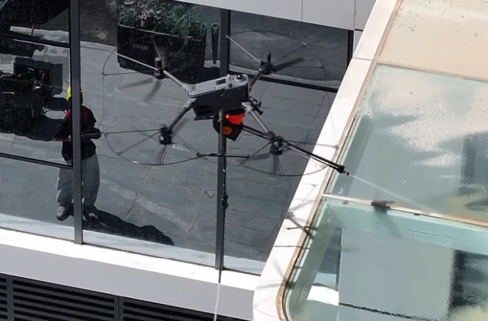 Drone spraying a glass facade seen from above